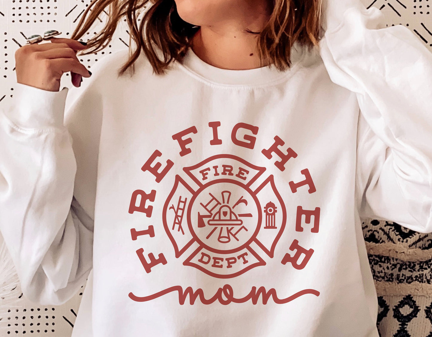 Woman wearing white sweatshirt with 'Firefighter Mom' text and badge design, suitable for Cricut and Silhouette projects.