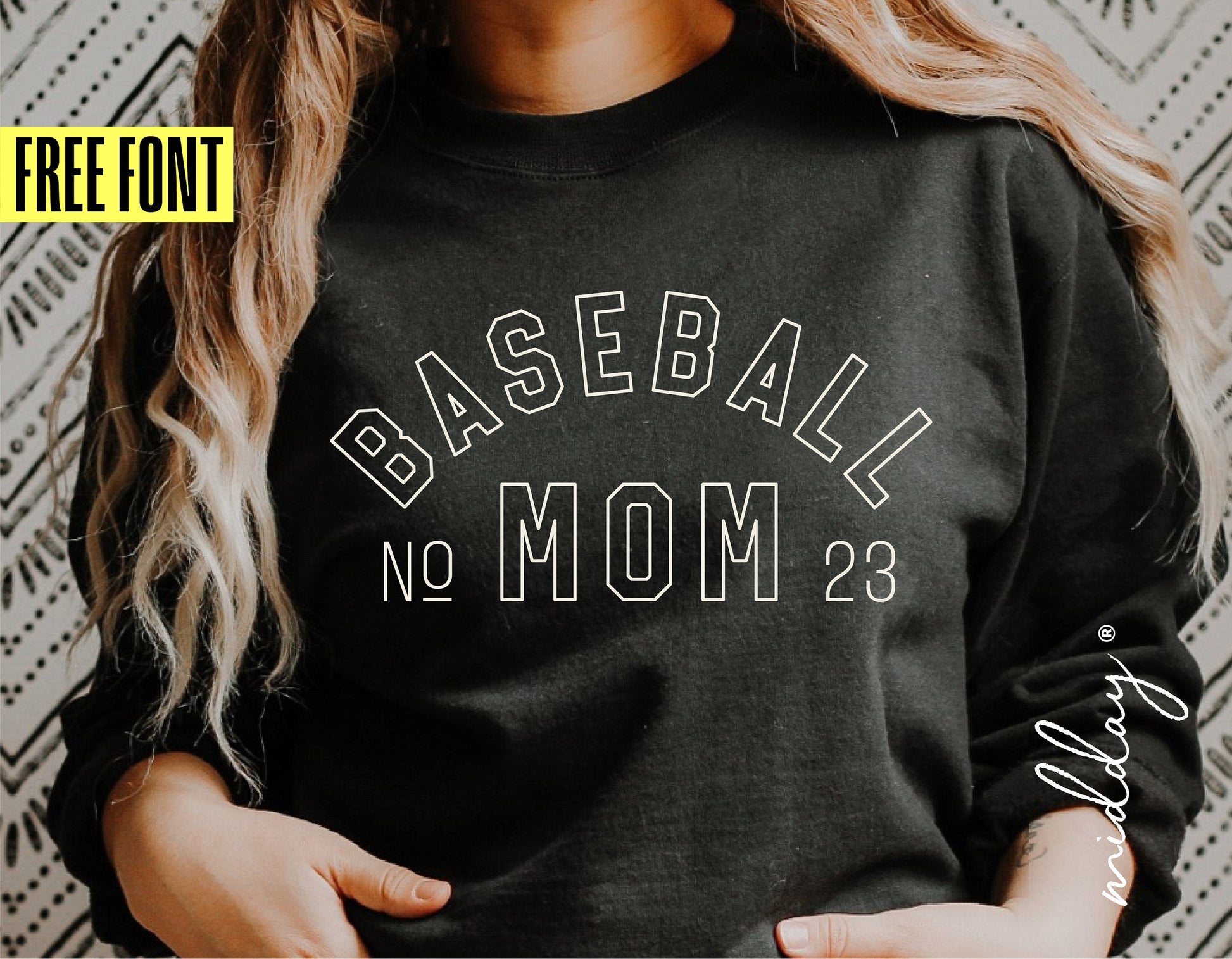 Woman wearing a black sweatshirt with 'Baseball Mom No 23' text design, showcasing customizable baseball mom SVG template with free font offer.