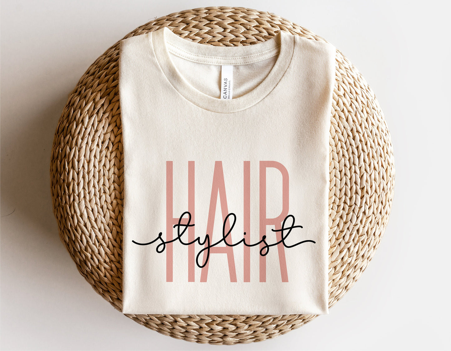 Beige t-shirt with 'Hair Stylist' design for Cricut and Silhouette projects, displayed on a woven basket.