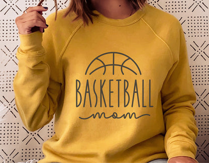 Woman wearing yellow sweatshirt with 'Basketball Mom' design, ideal for sports fan apparel options like shirts, hoodies, tumblers.