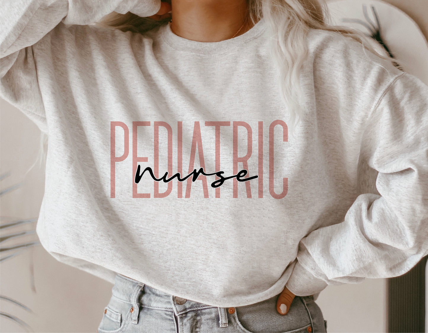 Sweatshirt with 'Pediatric Nurse' text design, worn by person with arms raised, showcasing nursing-themed apparel.