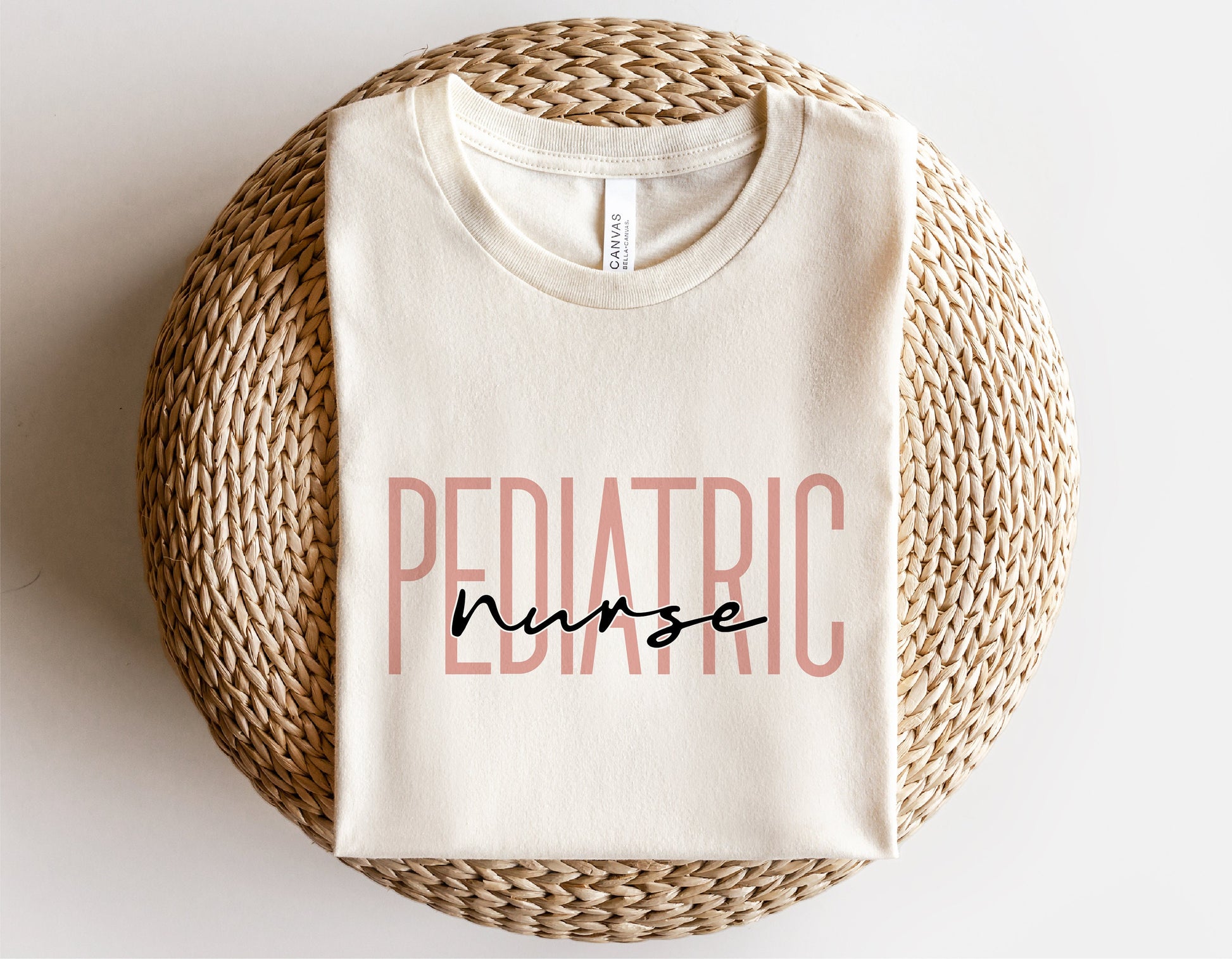 Cream t-shirt with 'Pediatric Nurse' text design, perfect for Cricut and Silhouette projects, displayed on a woven mat.