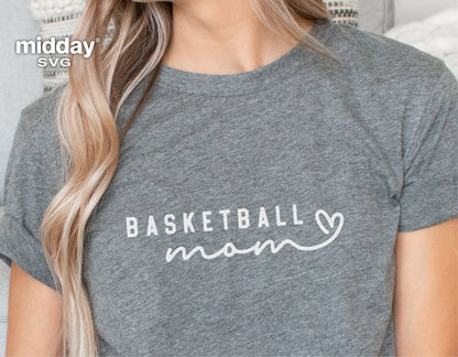 Close-up of a grey t-shirt featuring a white 'Basketball Mom' design with a heart, worn by a person with long blonde hair.