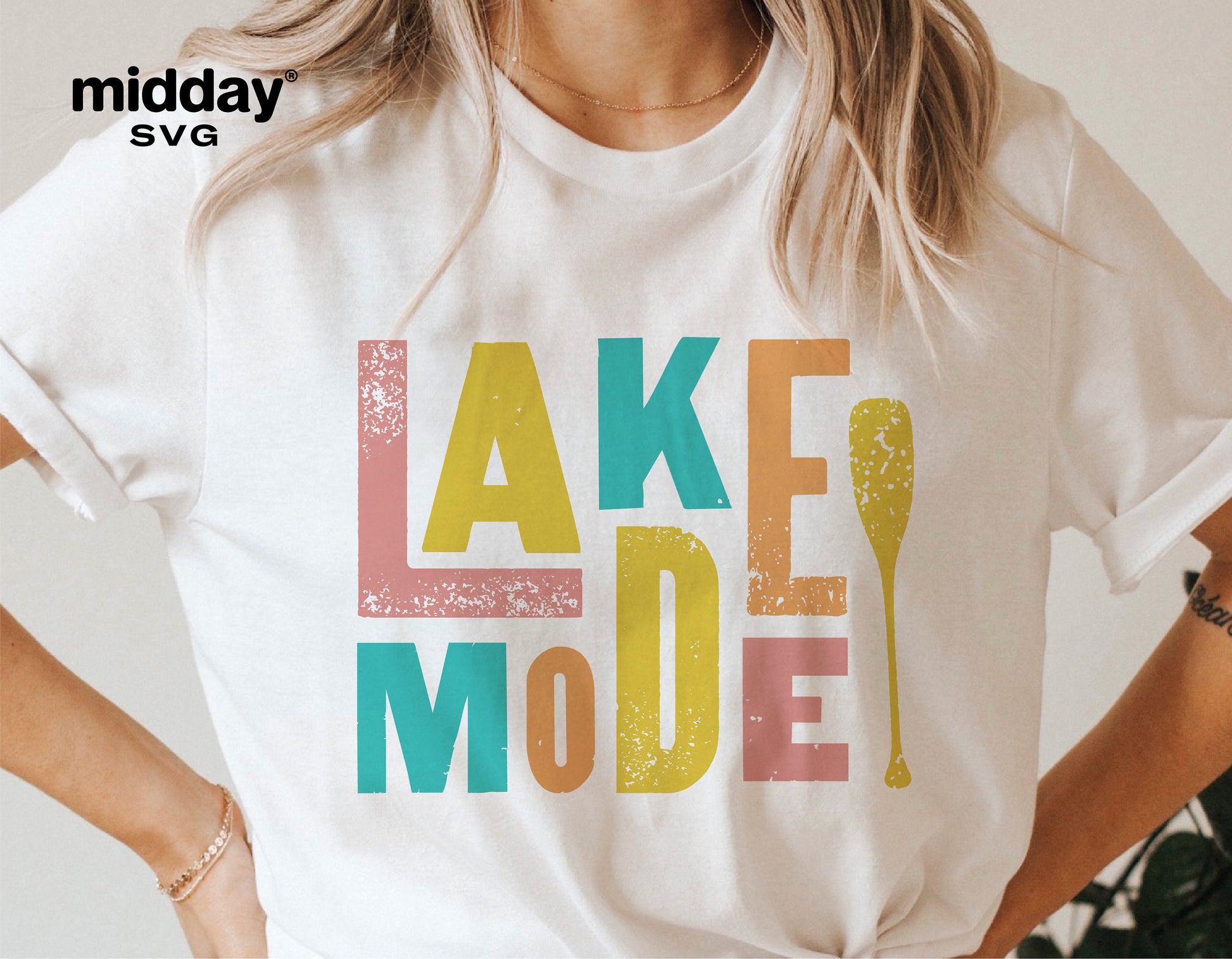 Woman wearing a white t-shirt with colorful text 'Lake Mode' featuring a paddle design, perfect for lake life enthusiasts.