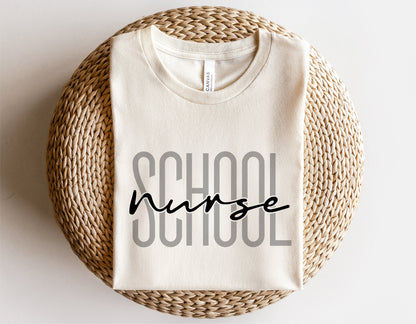 White t-shirt with 'School Nurse' text in bold and script font, perfect for school nurse gift, displayed on a woven surface.
