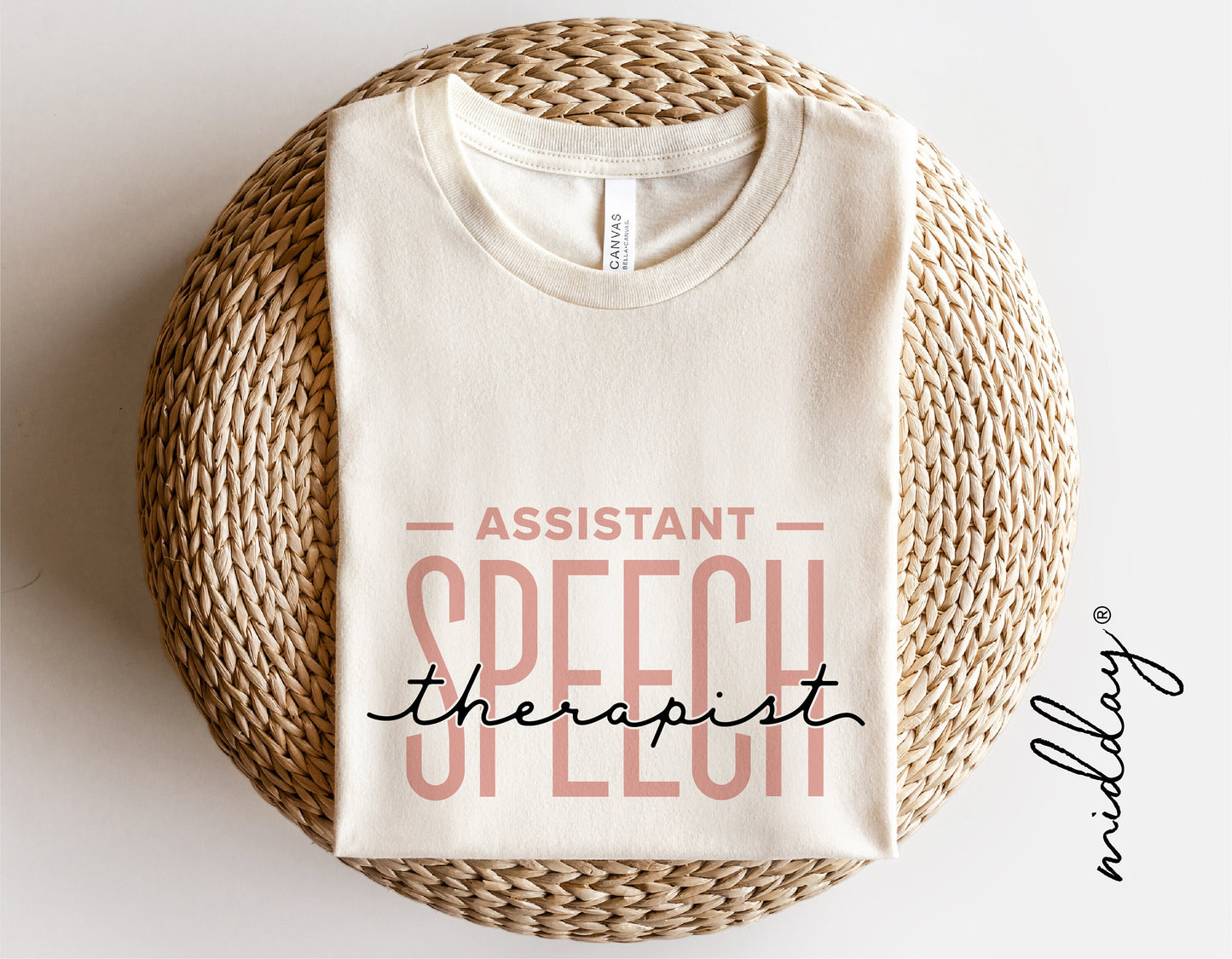 White t-shirt with 'Assistant Speech Therapist' design folded on a wicker chair, promoting speech therapy svg files for craft projects.