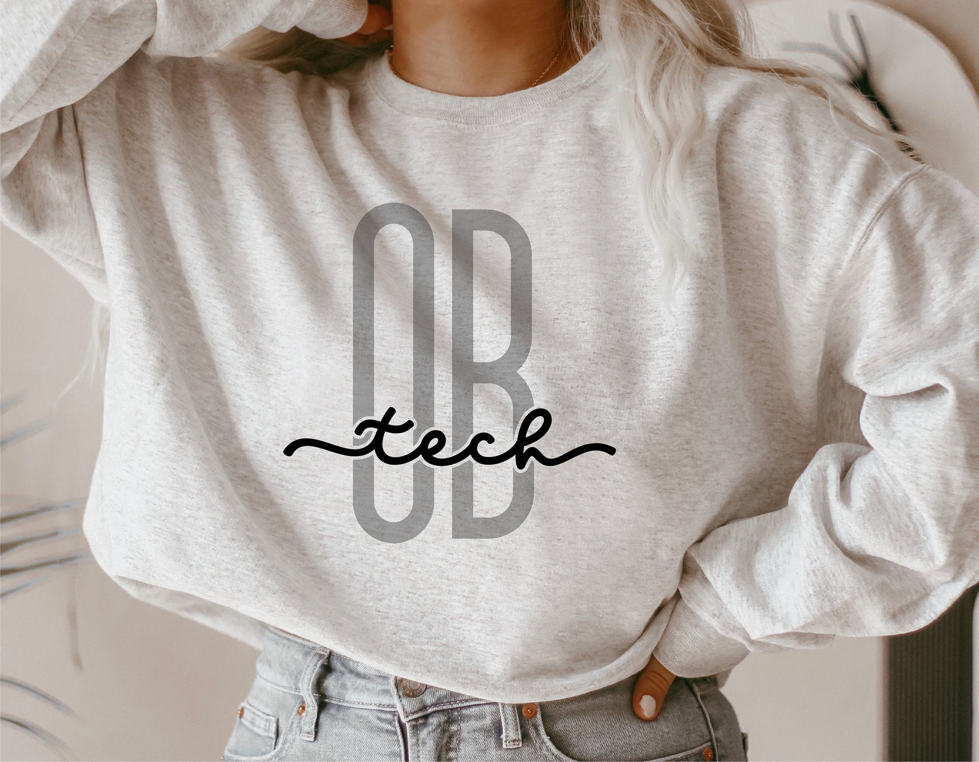 Woman wearing a gray sweatshirt with "OB Tech" design for obstetrical technicians.