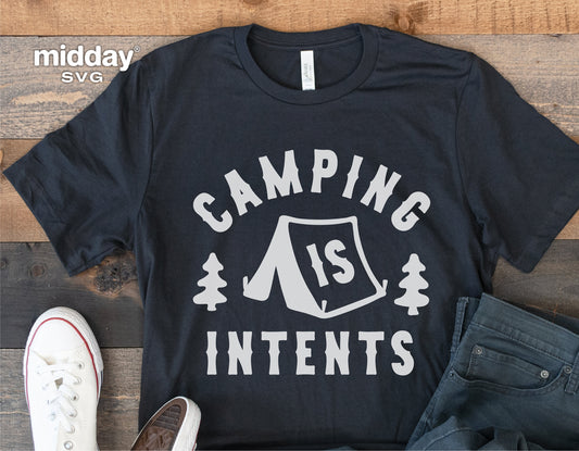 Black t-shirt with 'Camping is Intents' design, featuring a tent and trees, laid out on wooden surface with casual shoes and jeans.