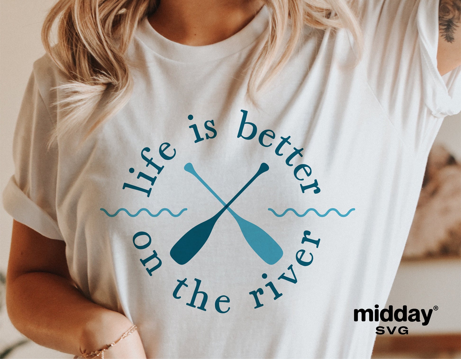 Woman wearing a white t-shirt with 'Life is Better on the River' graphic and crossed paddles design, perfect for river enthusiasts.