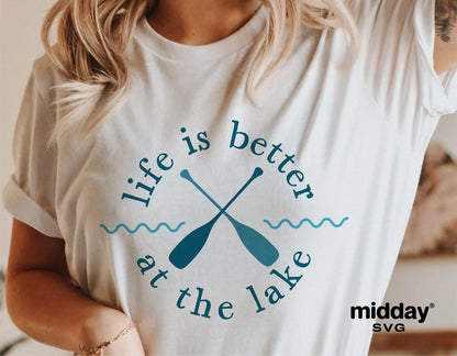 "Life is Better at the Lake" graphic on a white t-shirt, featuring crossed paddles in a relaxed summer lake theme.