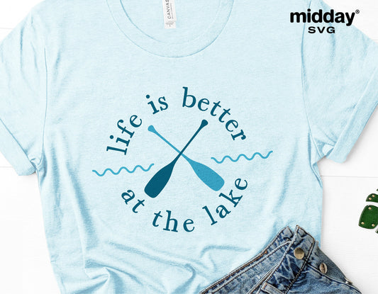 Light blue t-shirt with 'Life is better at the lake' design featuring crossed paddles, ideal for lake vacation or camping enthusiasts.