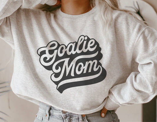 Woman wearing a sweatshirt featuring a 'Goalie Mom' design, ideal for hockey enthusiasts, available as SVG, PNG, and cut files for Cricut and Silhouette.