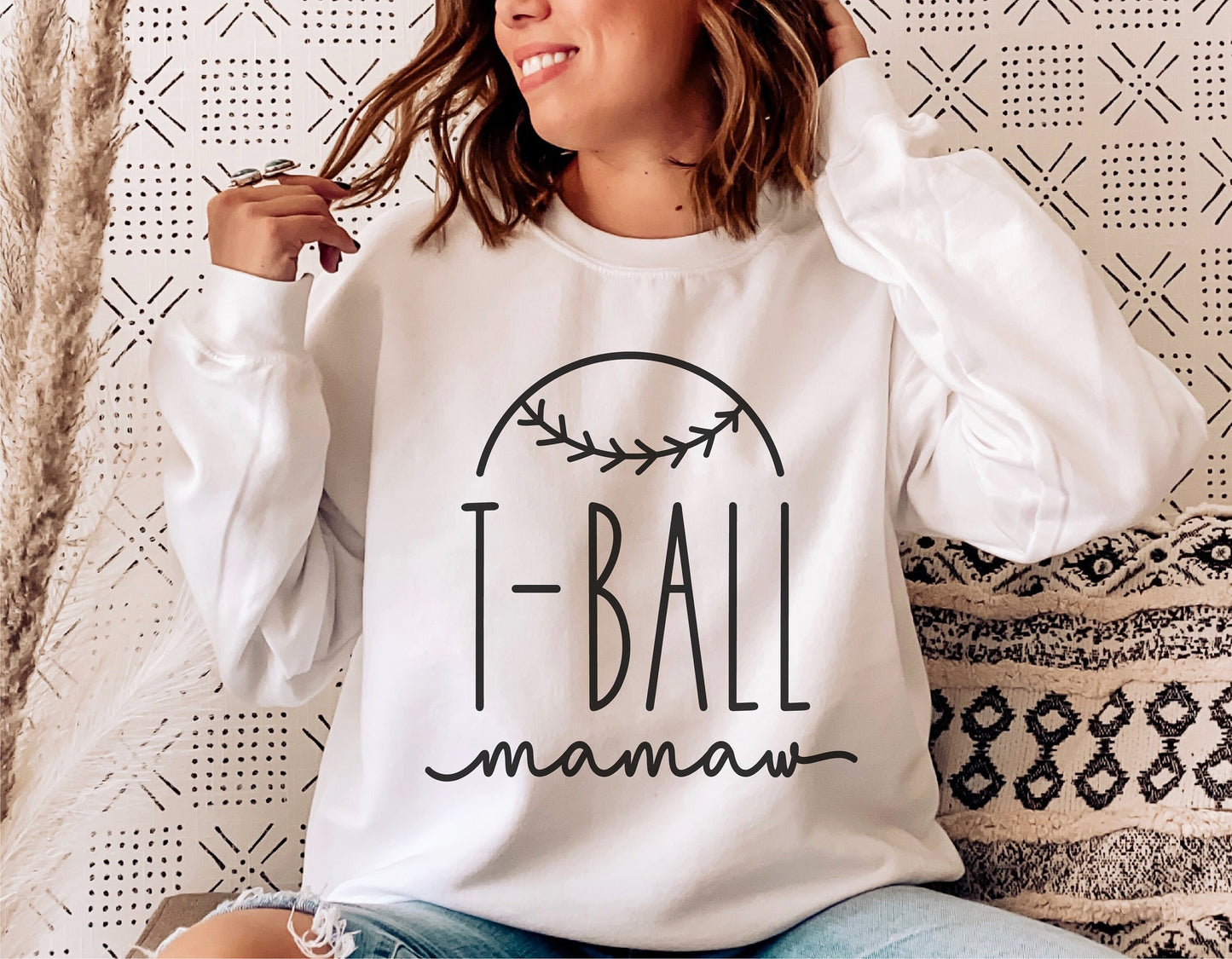 Woman wearing a white sweatshirt with "T-Ball mamaw" design, perfect for Cricut and Silhouette projects, featuring sporty baseball theme.