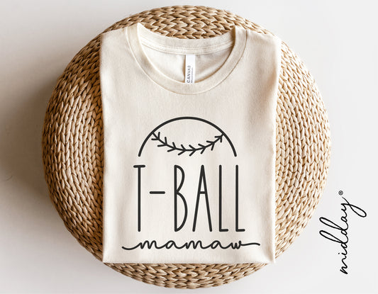 White T-ball Mamaw shirt with baseball graphic, folded on a woven round mat, ideal for Cricut and Silhouette projects.