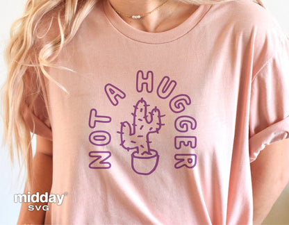 Woman wearing pink shirt with "Not a Hugger" funny cactus graphic design; suitable for Cricut and Silhouette projects.