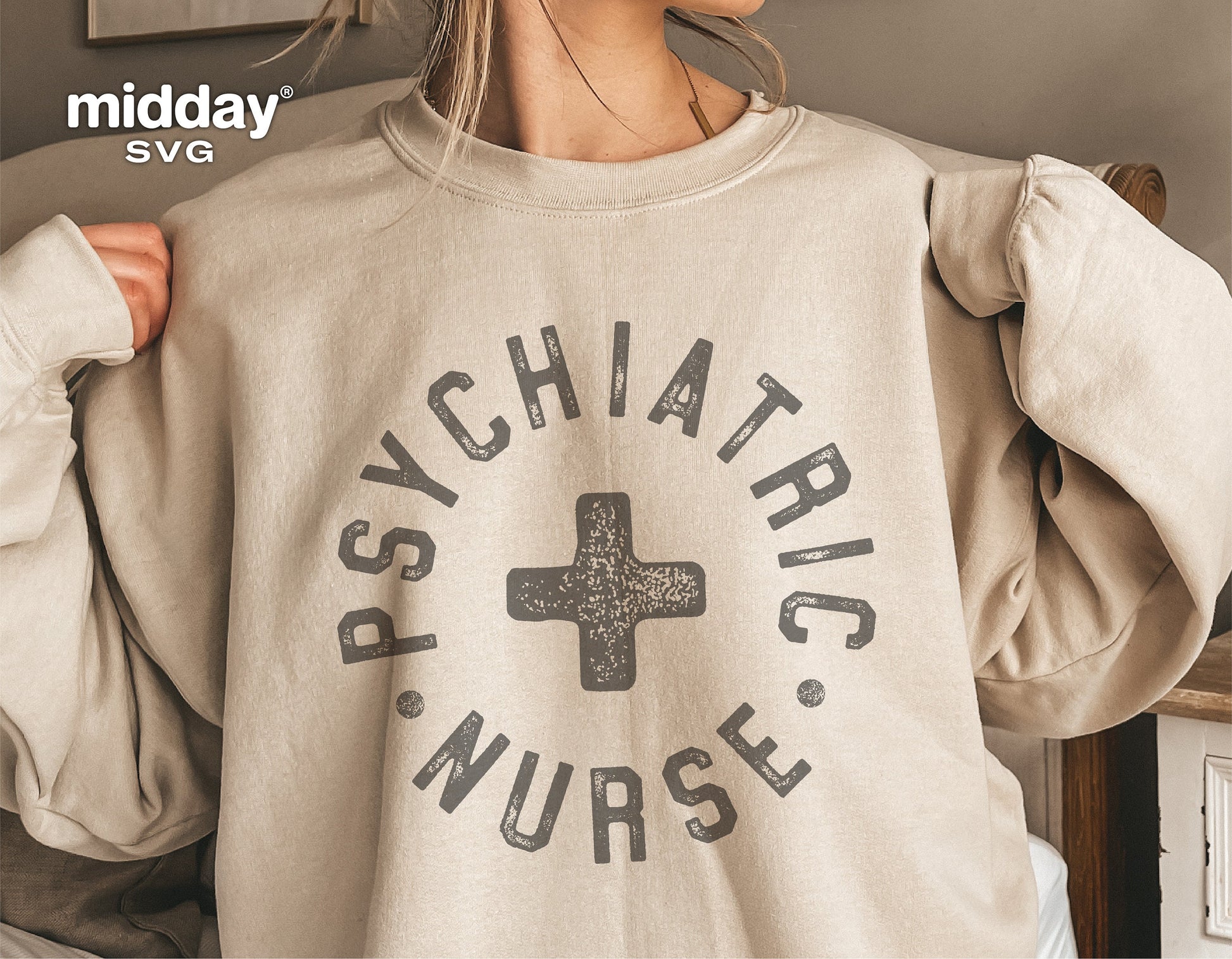Person wearing a beige sweatshirt with 'Psychiatric Nurse' text and cross design, promoting psychiatric nurse SVG files for crafts.