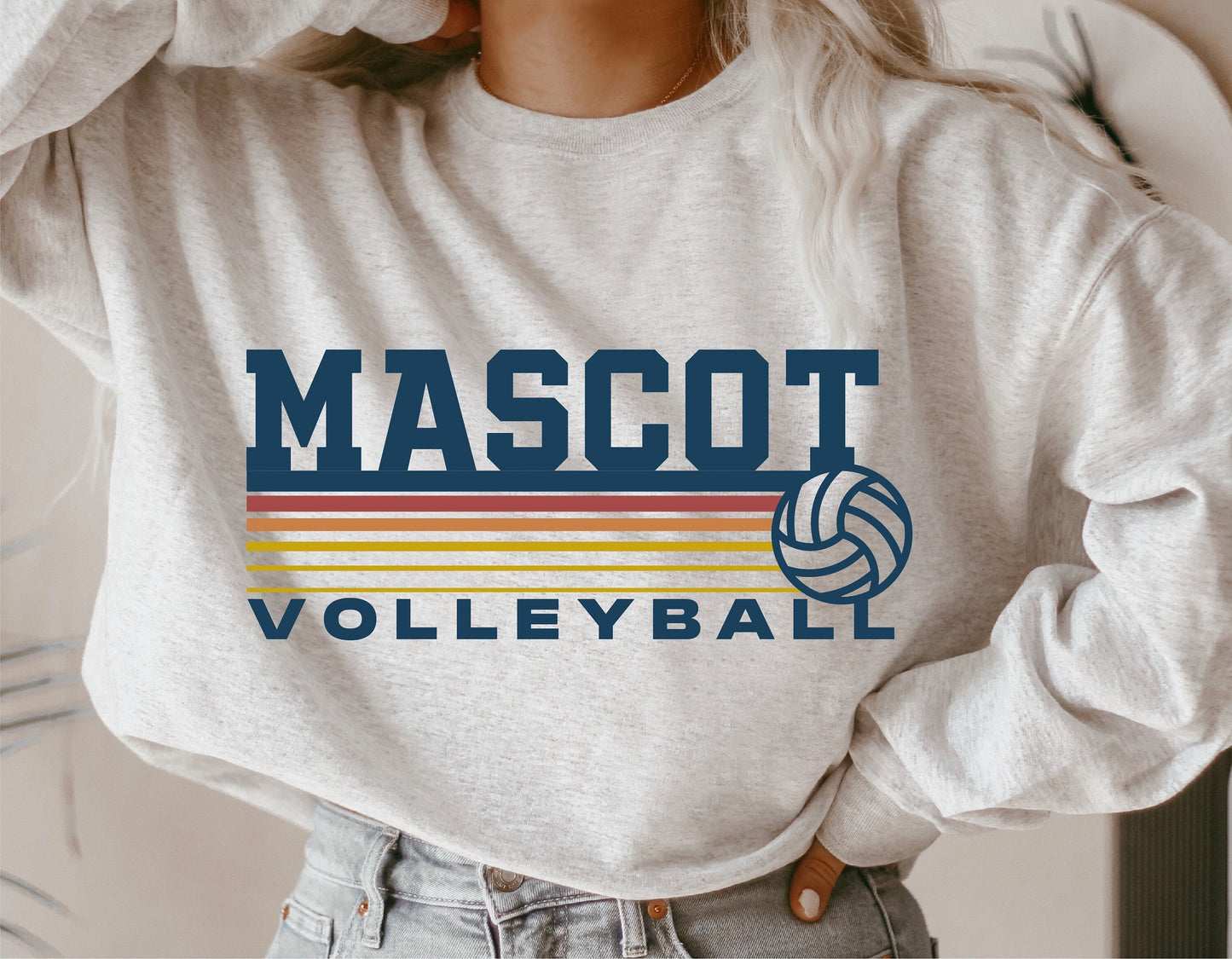 Woman wearing a sweatshirt displaying a 'Mascot Volleyball' design with a volleyball logo and colorful stripes.